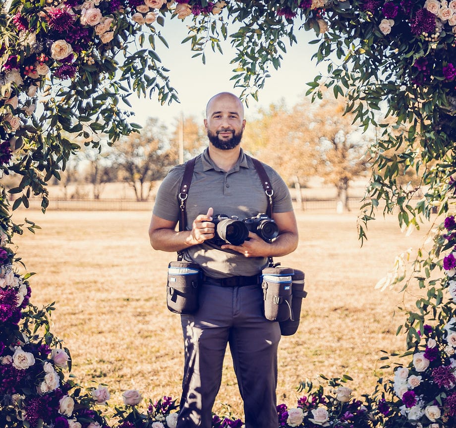 A studly wedding photographer holding a video camera and stills camera